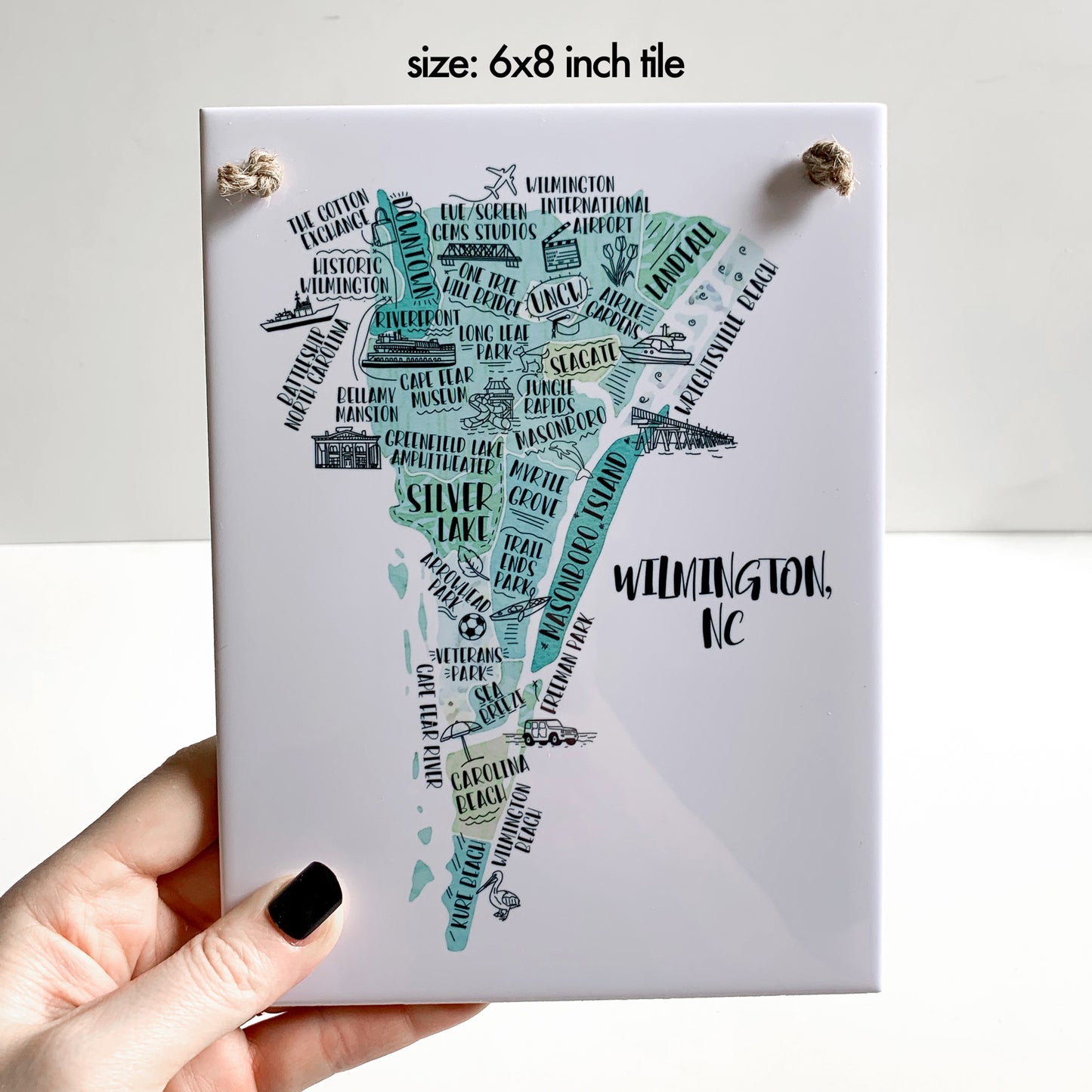 A hand holding a rectangle tile sign with a illustrated map on it, in the 6x8 inch size
