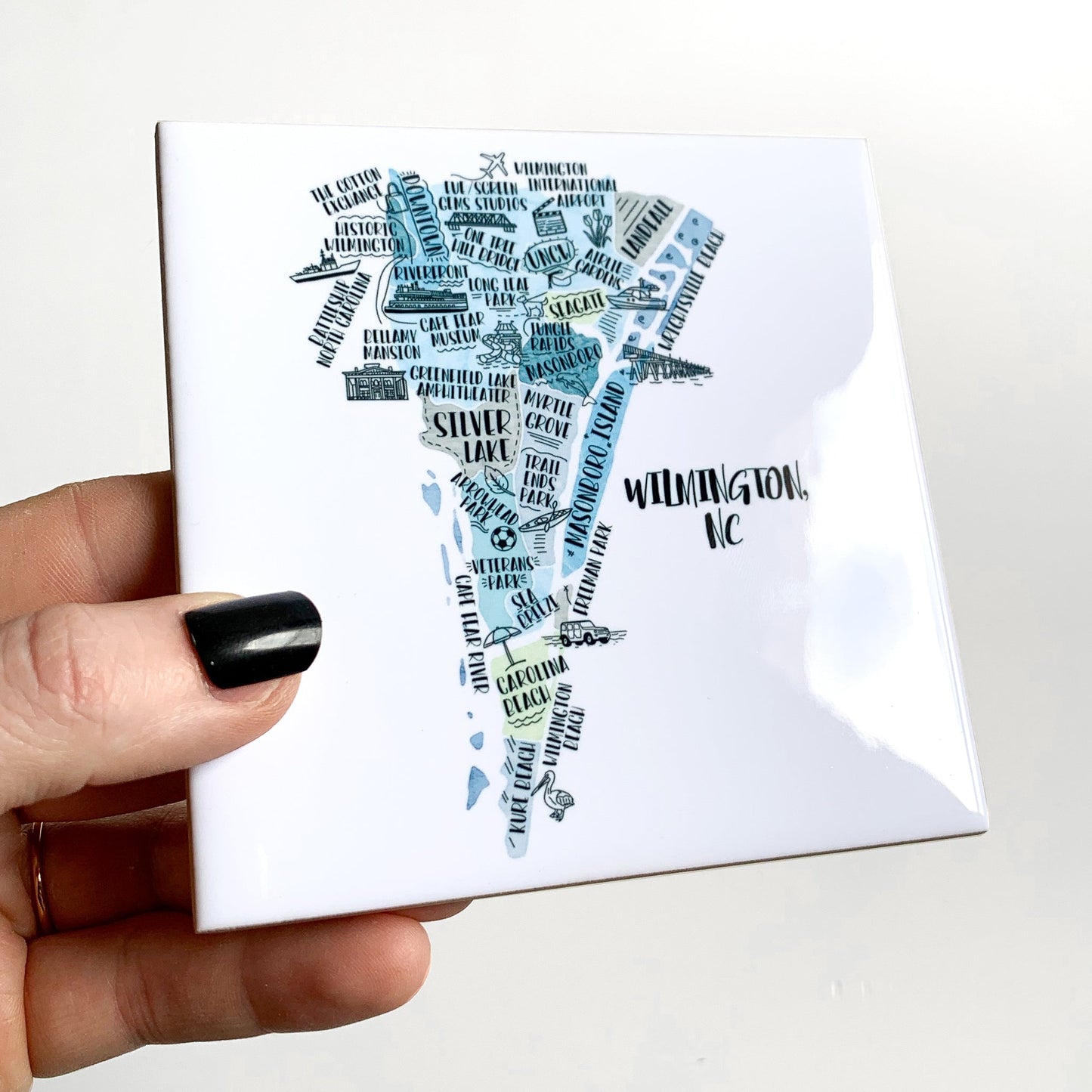 A hand holding a ceramic coaster with a tourist map on it, showing the glossy finish