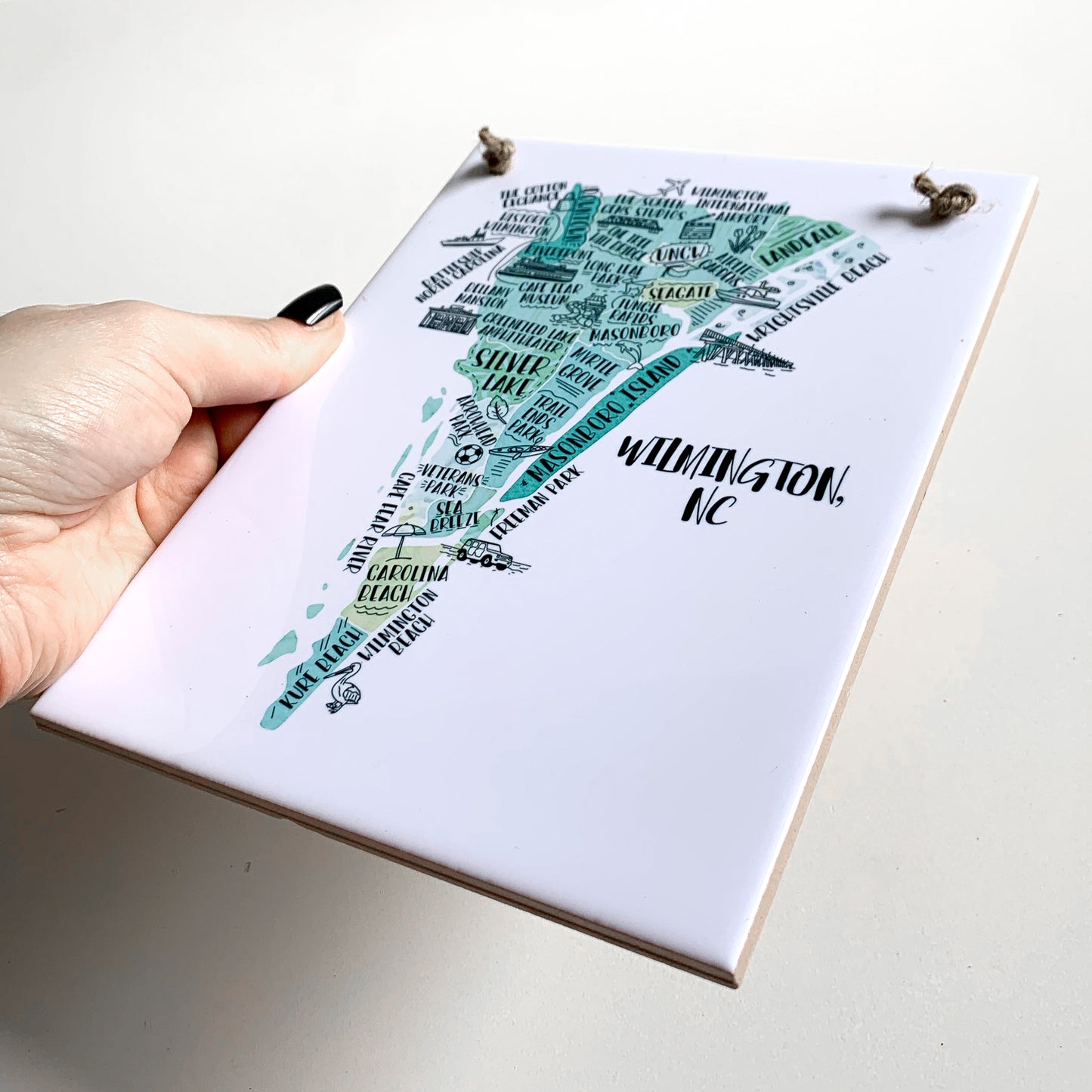 A hand holding a rectangle tile sign with a tourist map on it, showing the ceramic tile edges