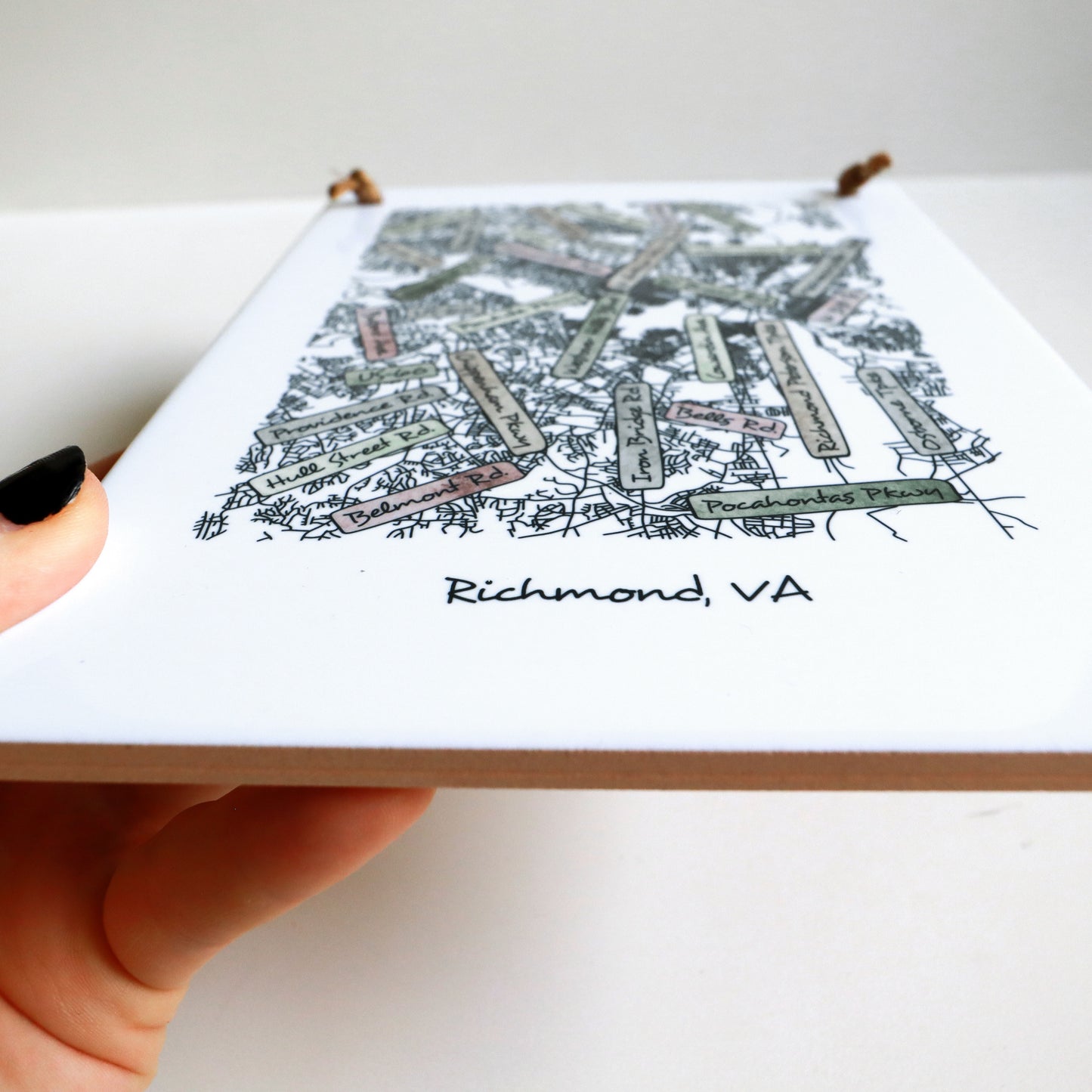 A hand holding a custom city street map on a rectangle tile sign, showing the tile edges