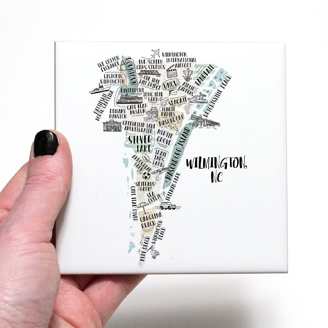 A hand holding a coaster with an illustrated map of Wilmington NC on it - in the color beige