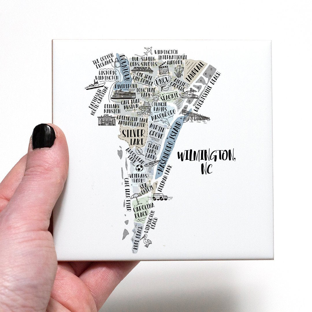 A hand holding a coaster with an illustrated map of Wilmington NC on it - in the color gray