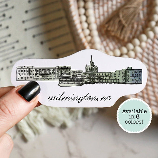 A hand holding a sticker of a city drawing of Wilmington North Carolina - Sparks House Co
