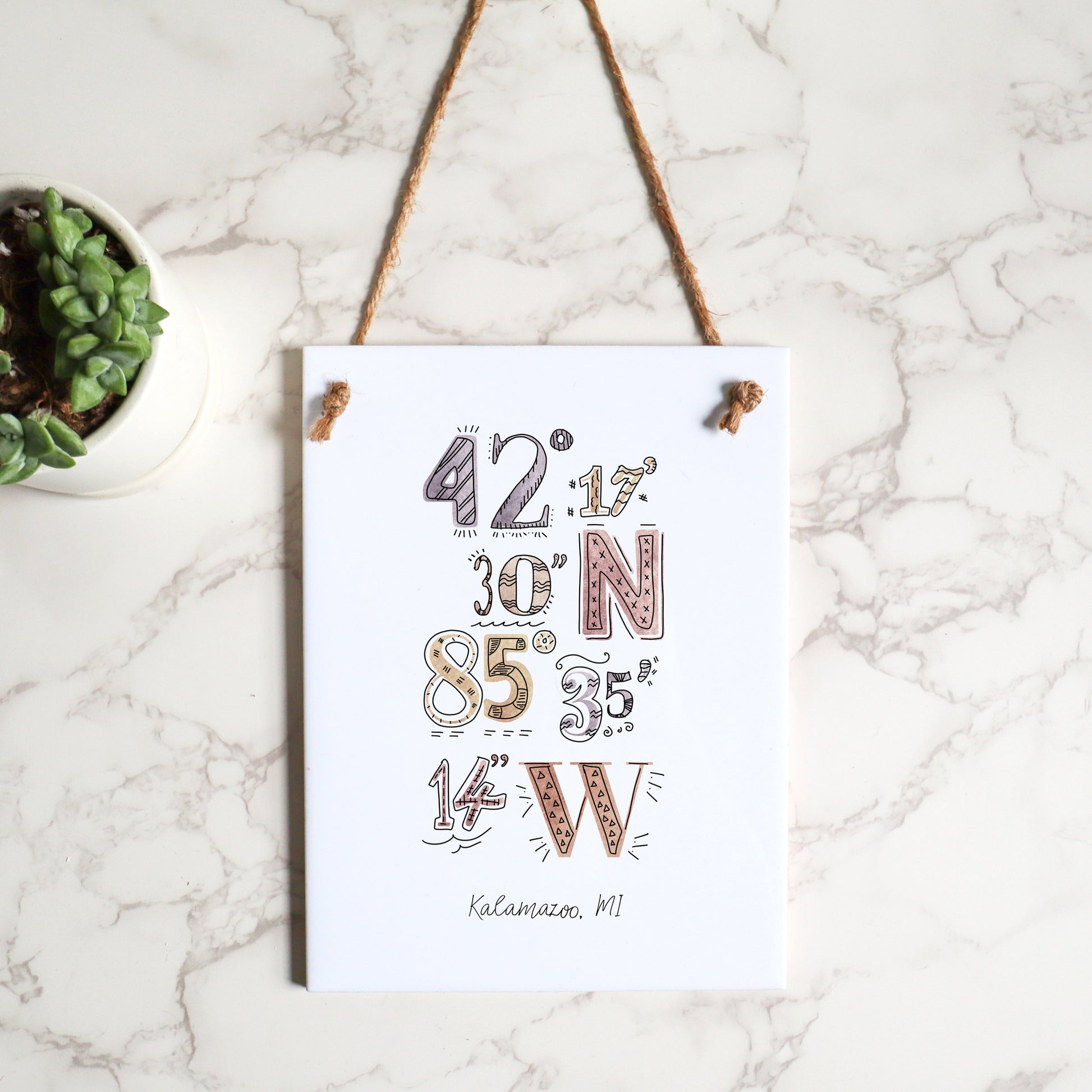 Flat lay of a rectangle ceramic tile sign, featuring the custom drawing of the coordinates for your city