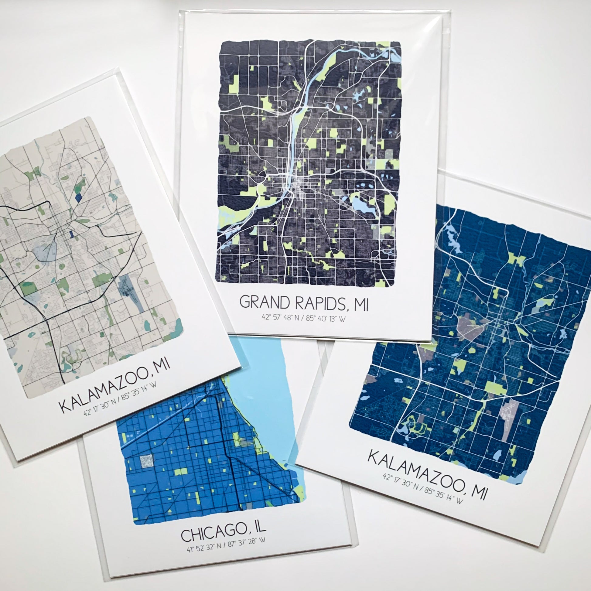 Four city map prints in different colors on a table, all in plastic sleeves