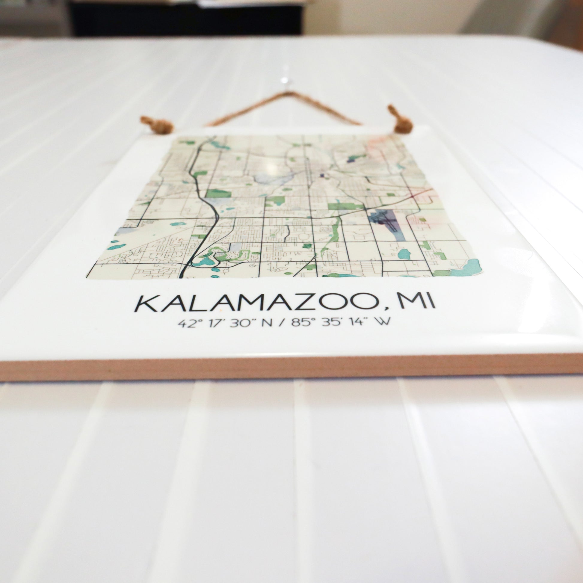 A close-up of a city map tile sign sitting on a table, showing the ceramic tile edges.