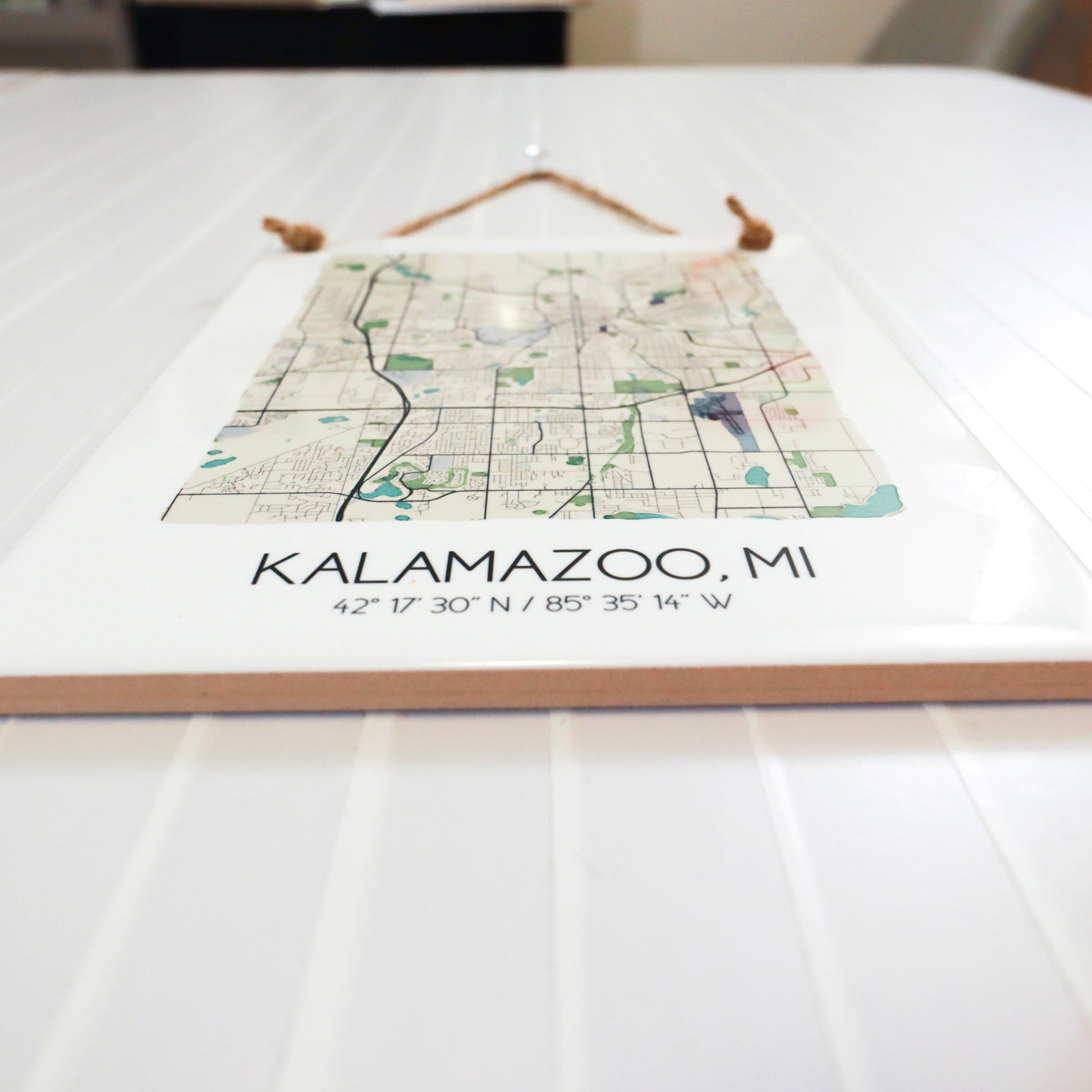 A close-up of a city map tile sign sitting on a table, showing the ceramic tile edges