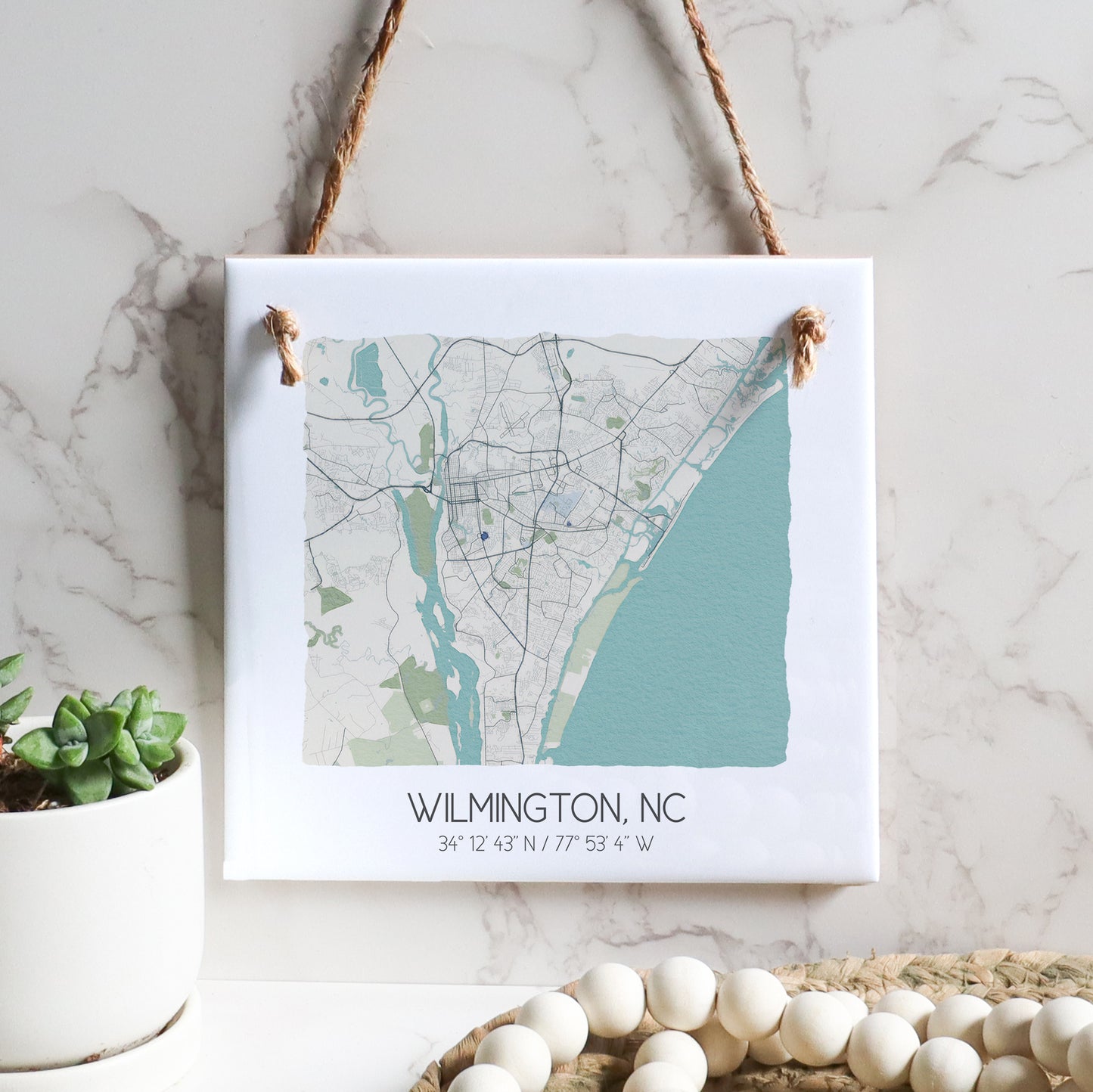 A city map of Wilmington North Carolina on a square ceramic tile sign hanging on a wall, in the color beige