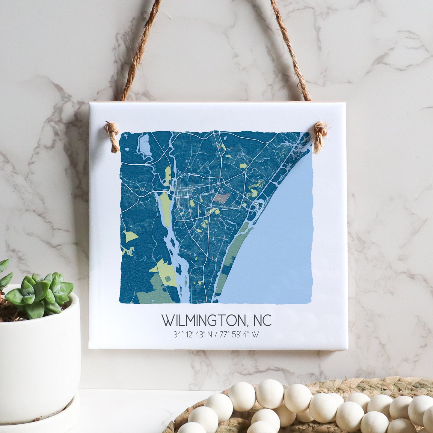 A city map of Wilmington North Carolina on a square ceramic tile sign hanging on a wall, in the color blue