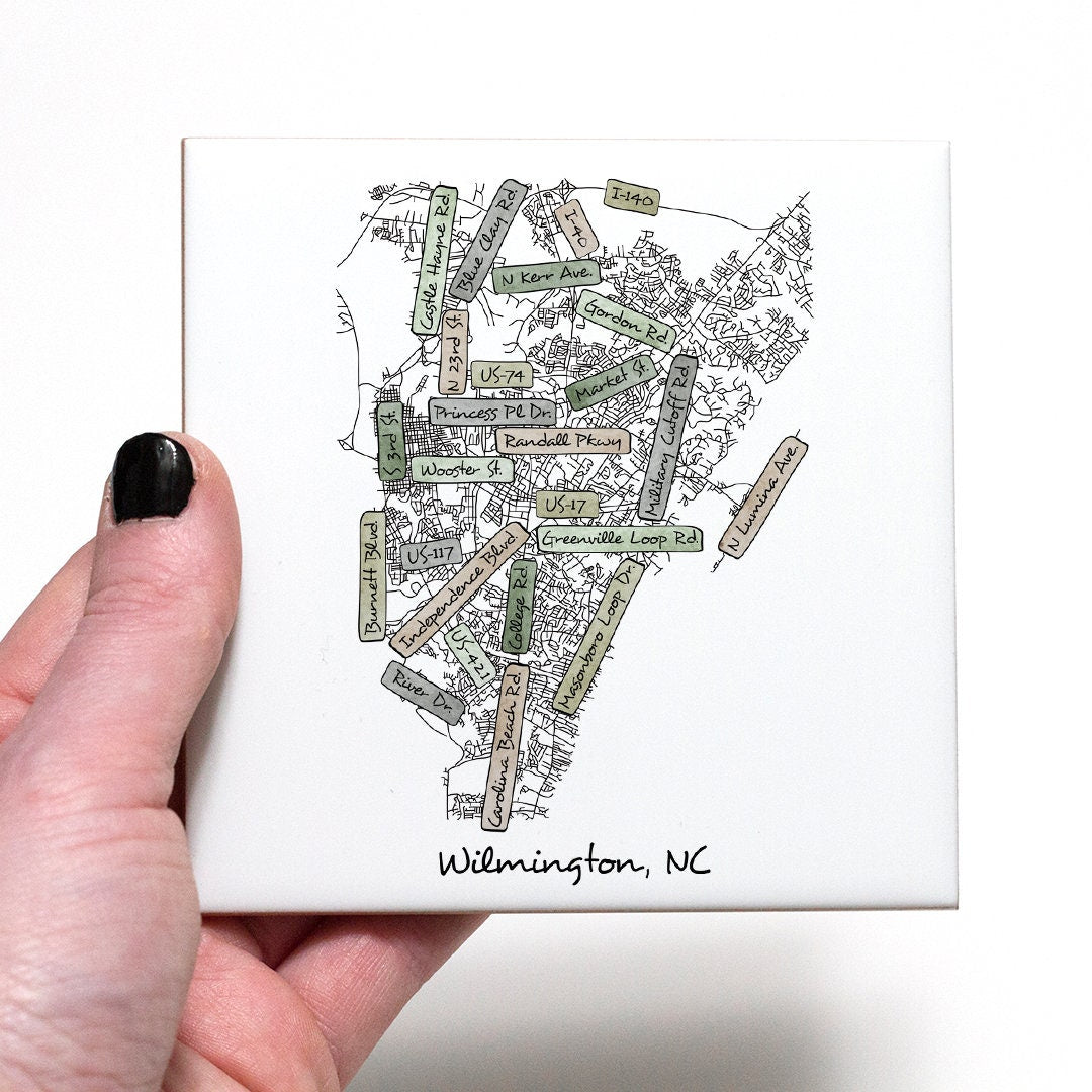 A hand holding a ceramic coaster with a street map of Wilmington NC on it - in the color earthy
