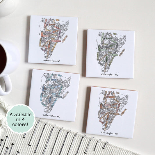 A set of 4 ceramic coasters sitting on a table with a Wilmington NC street map on them, in four different colors
