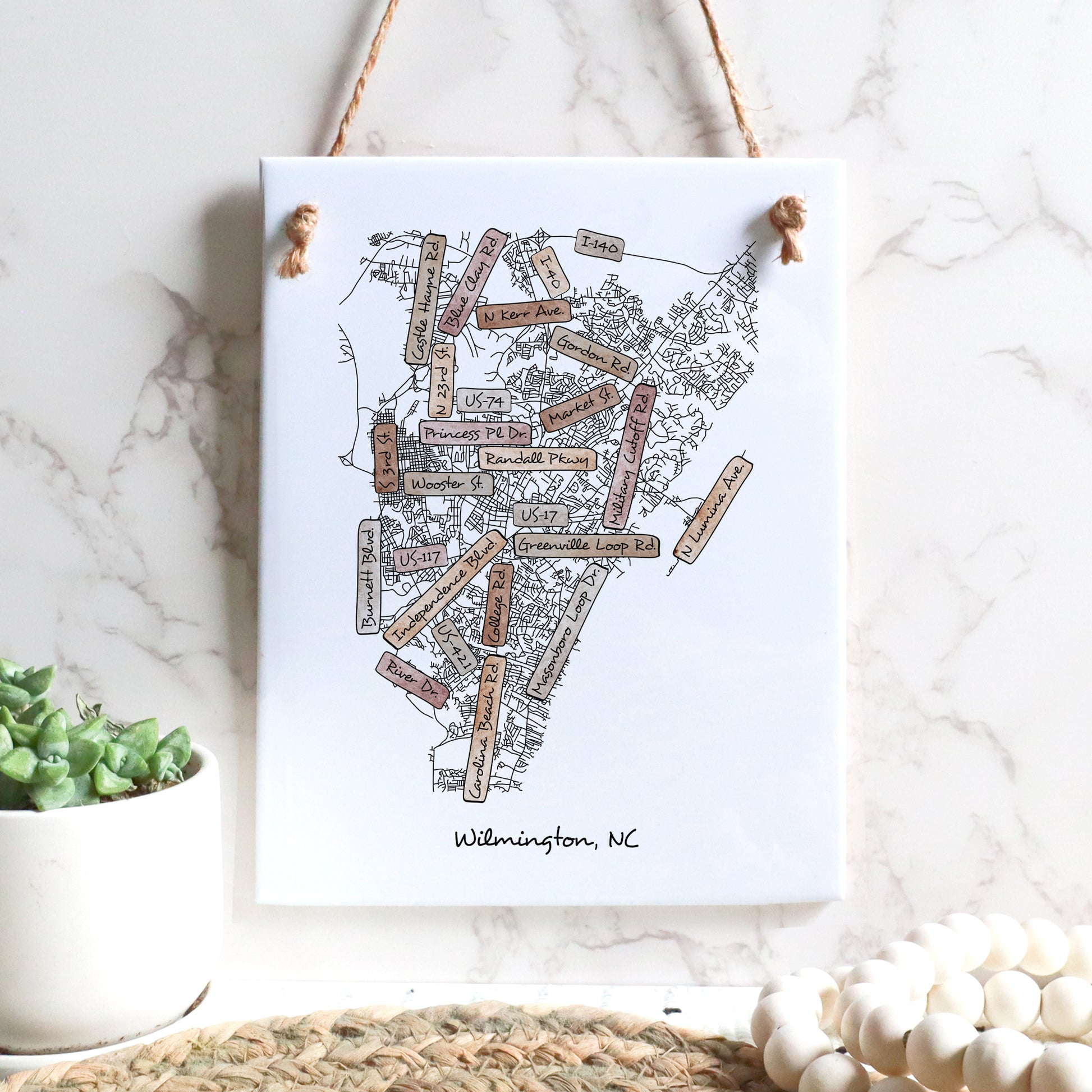 A street map drawing of Wilmington NC on a rectangle tile sign hanging on a wall - in the color boho