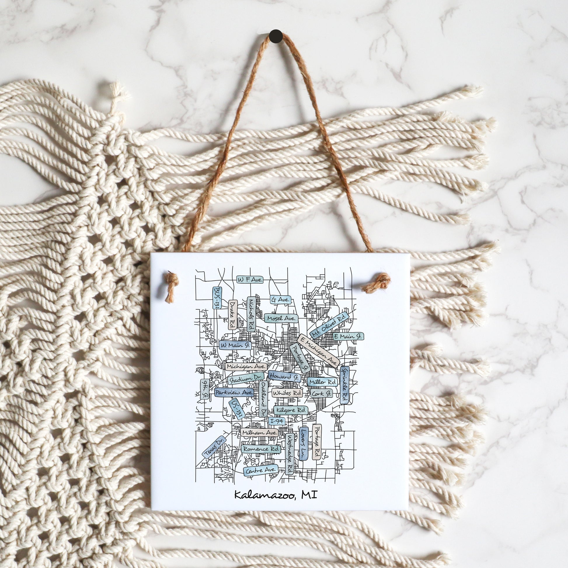 A flat lay of a custom city street map square tile sign, showing how it hangs from a hemp string tie