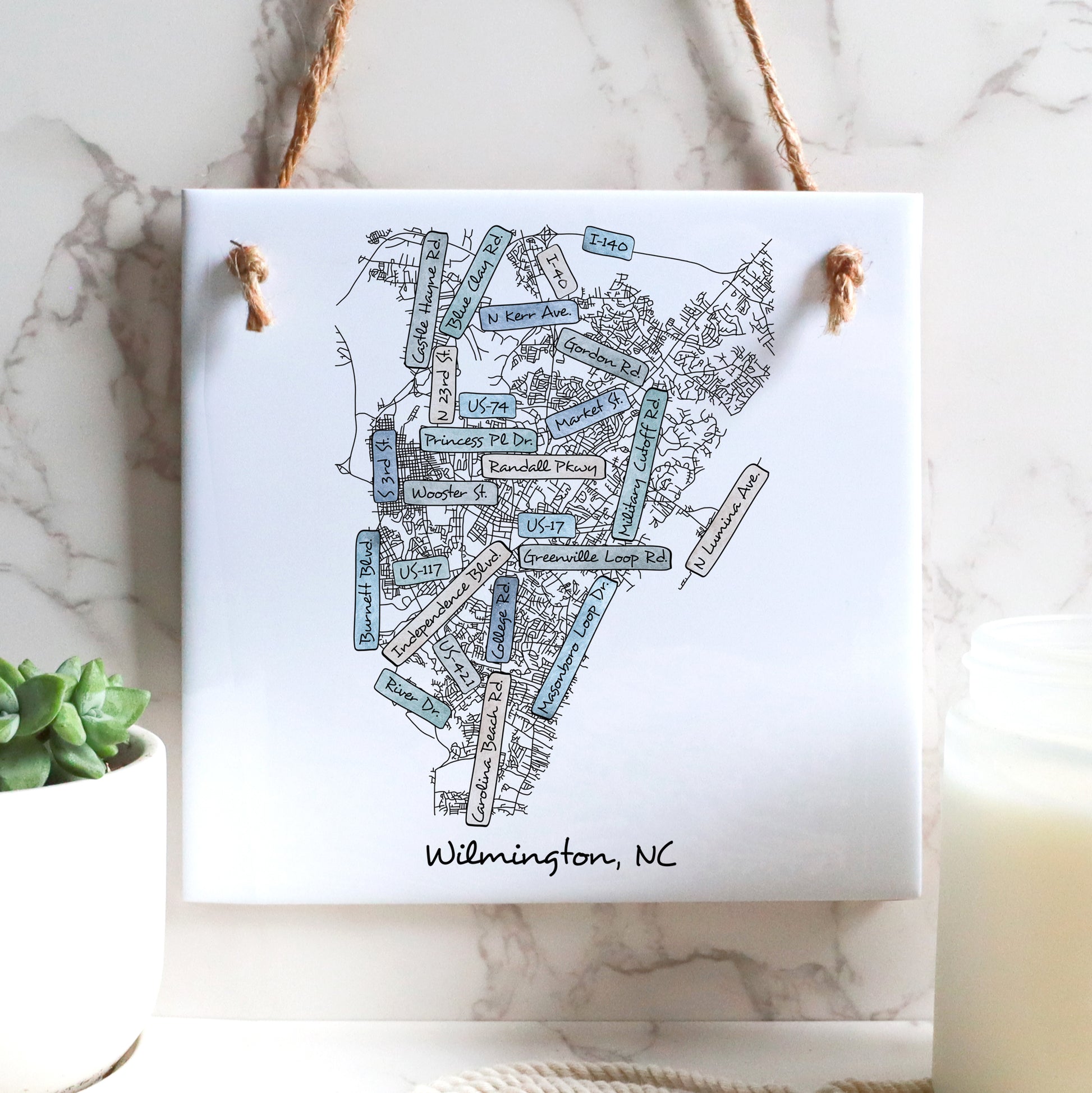A street map of Wilmington North Carolina on a ceramic square tile sign hanging on a wall - in the color coastal