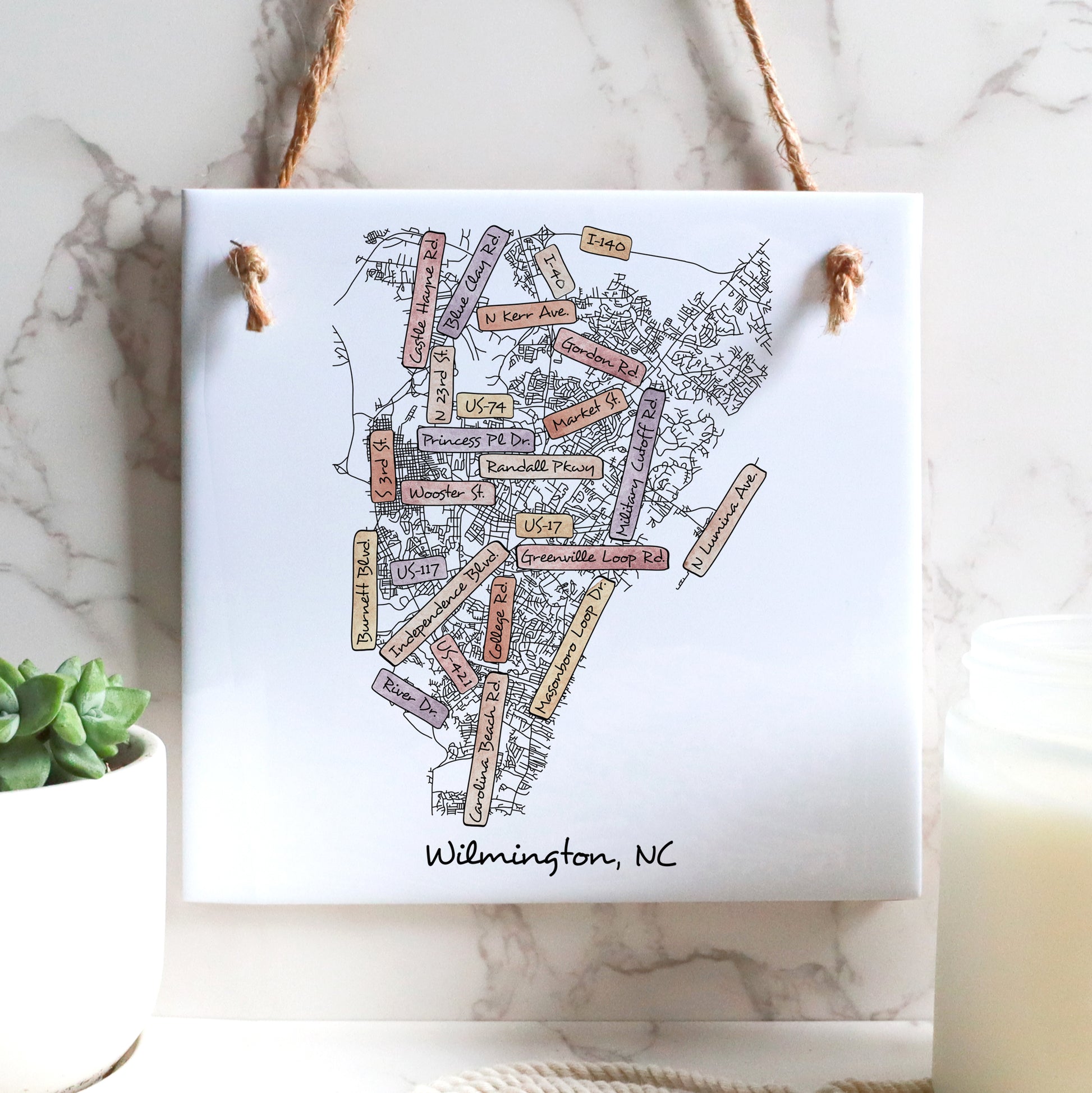 A street map of Wilmington North Carolina on a ceramic square tile sign hanging on a wall - in the color sunset