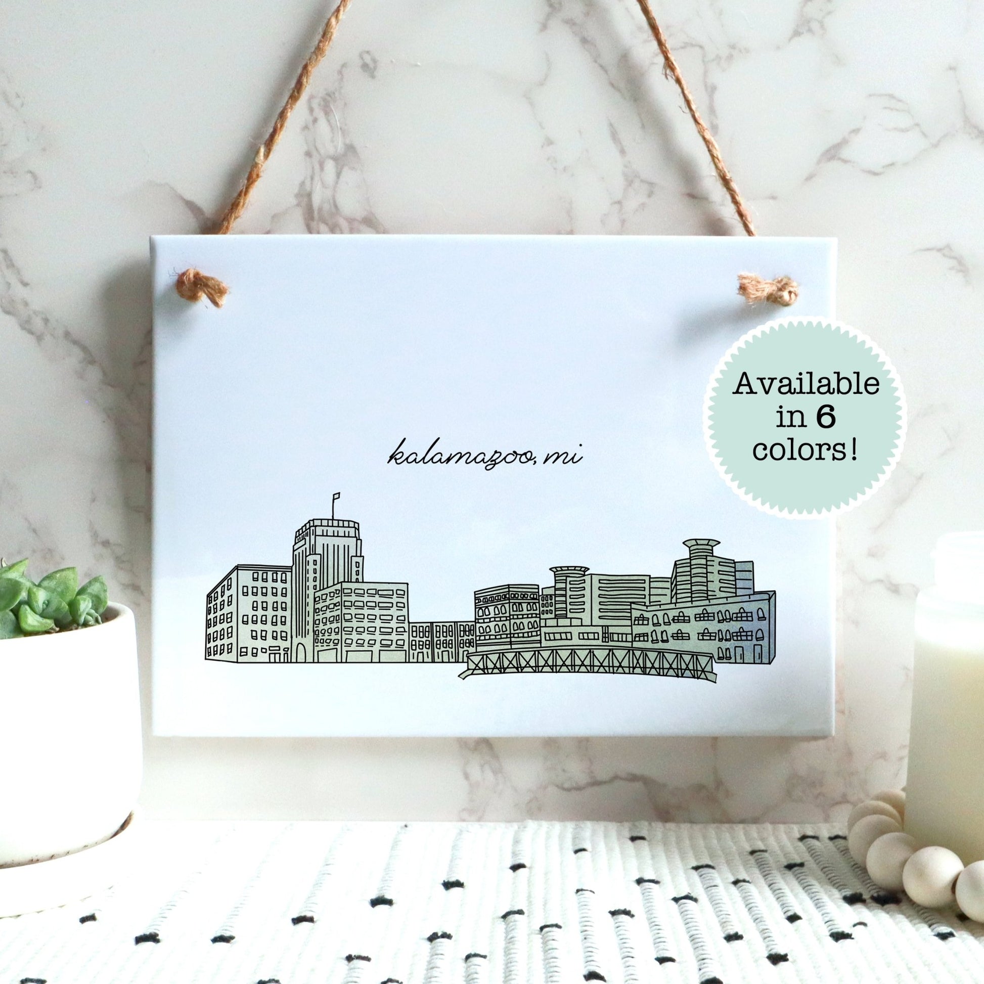 A Kalamazoo MI souvenir of a drawing of the city skyline on a rectangle tile sign, hanging on a wall - in the color green