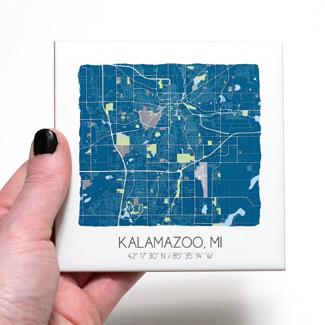 A hand holding a ceramic map coaster of Kalamazoo MI - in the color blue