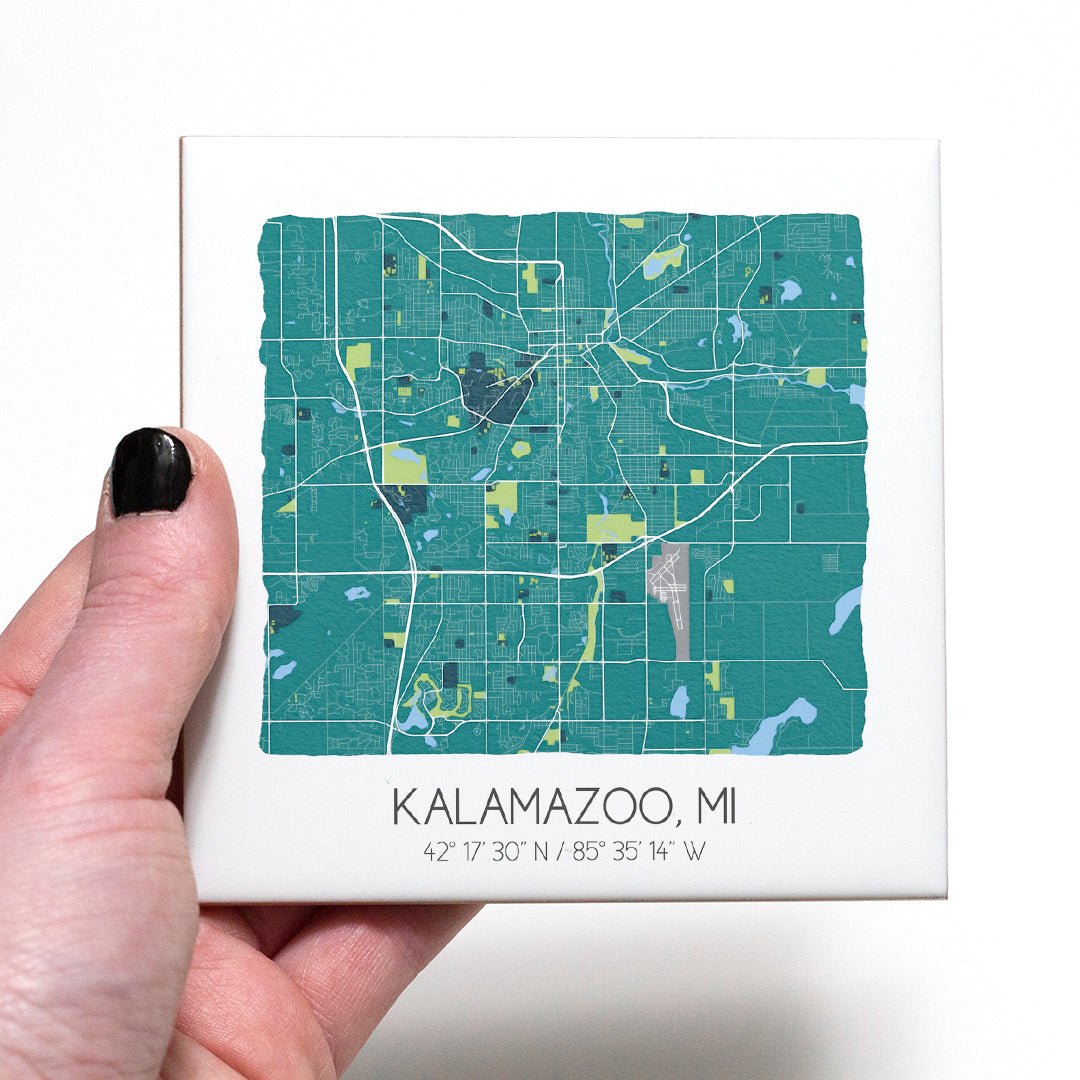 A hand holding a ceramic map coaster of Kalamazoo MI - in the color teal