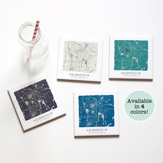 A set of 4 Kalamazoo MI map coasters sitting on a table with a glass, in four different colors - Sparks House Co