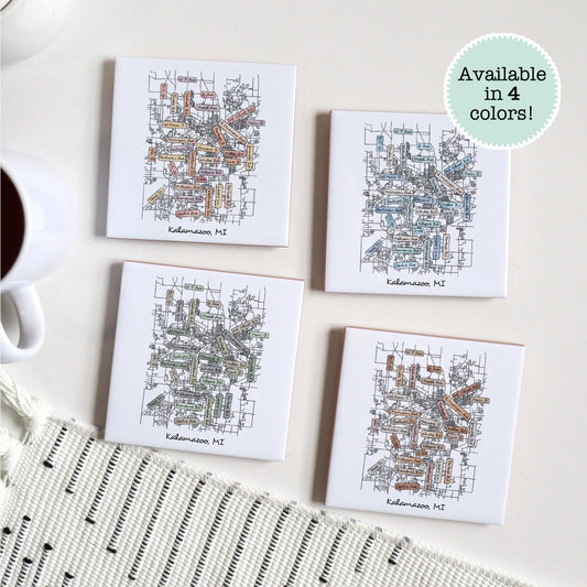 A set of 4 ceramic coasters sitting on a table with a Kalamazoo MI street map on them, in four different colors
