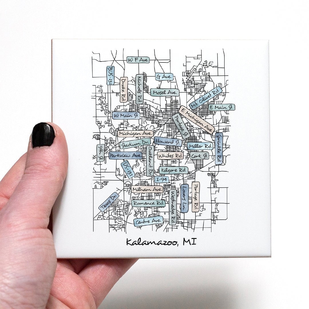 A hand holding a ceramic coaster with a street map of Kalamazoo MI on it - in the color coastal
