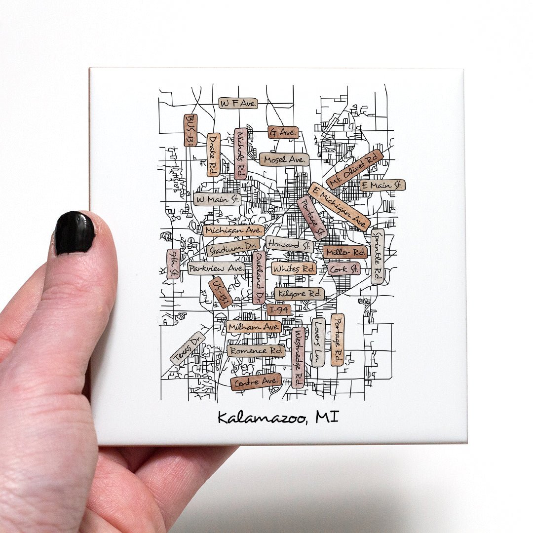 A hand holding a ceramic coaster with a street map of Kalamazoo MI on it - in the color boho