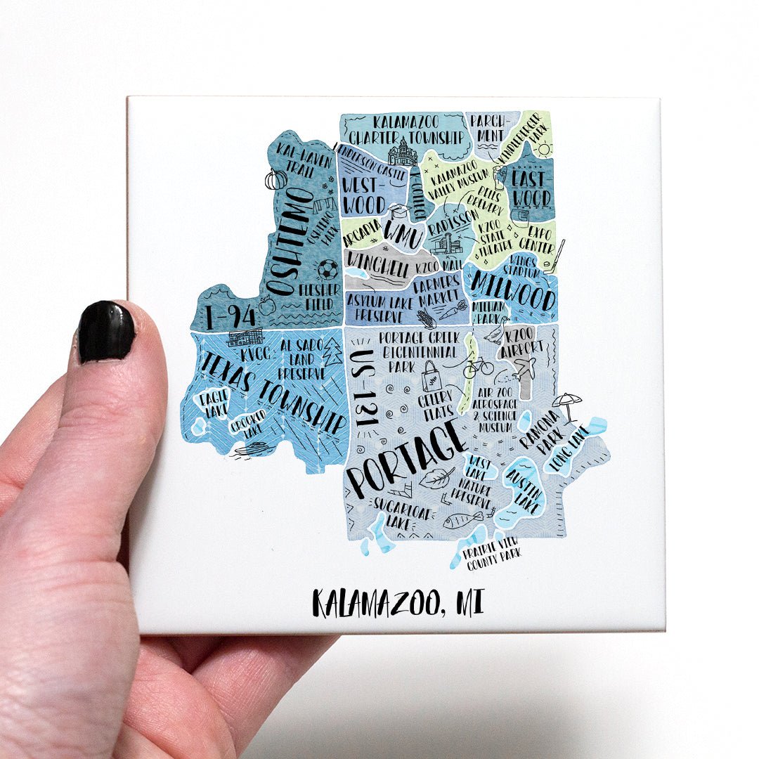 A hand holding a coaster with an illustrated map of Kalamazoo MI on it - in the color blue
