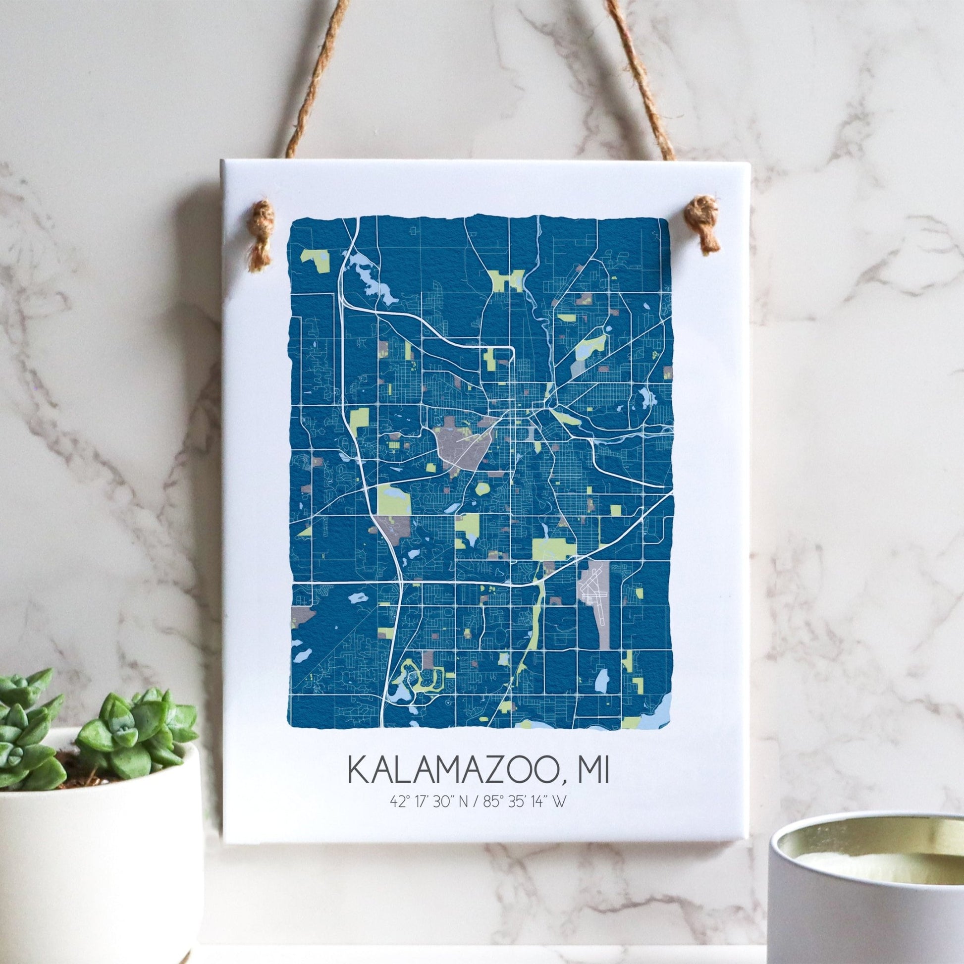 A Kalamazoo MI city map on a ceramic rectangle tile sign hanging on a wall, in blue
