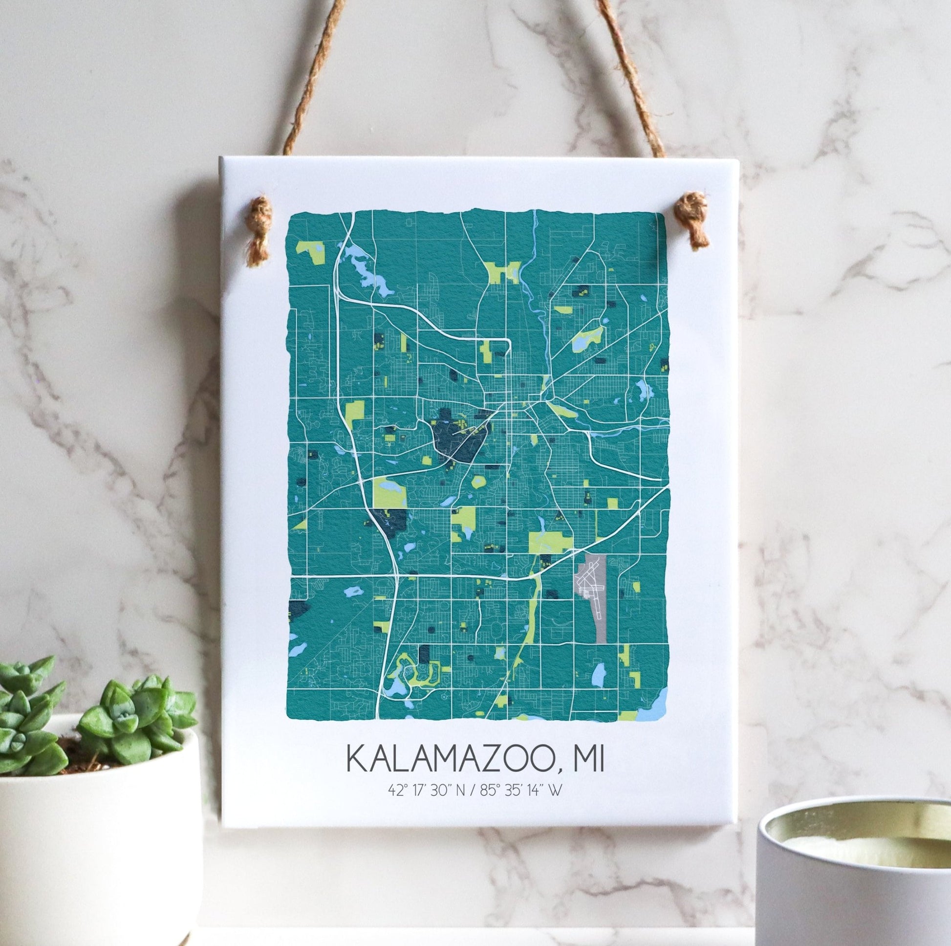 A Kalamazoo MI city map on a ceramic rectangle tile sign hanging on a wall, in teal