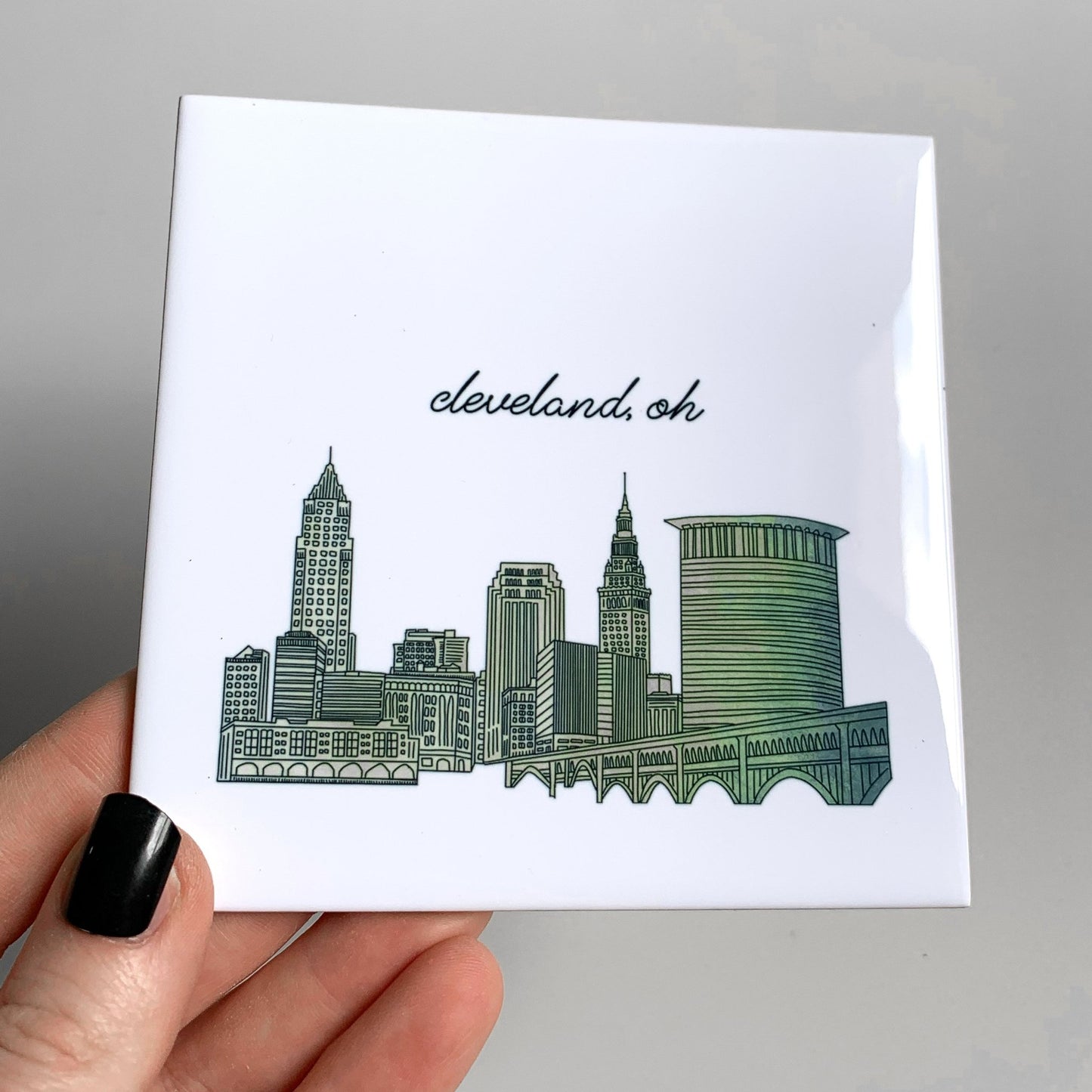 A hand holding a city skyline coaster - showing the glossy finish