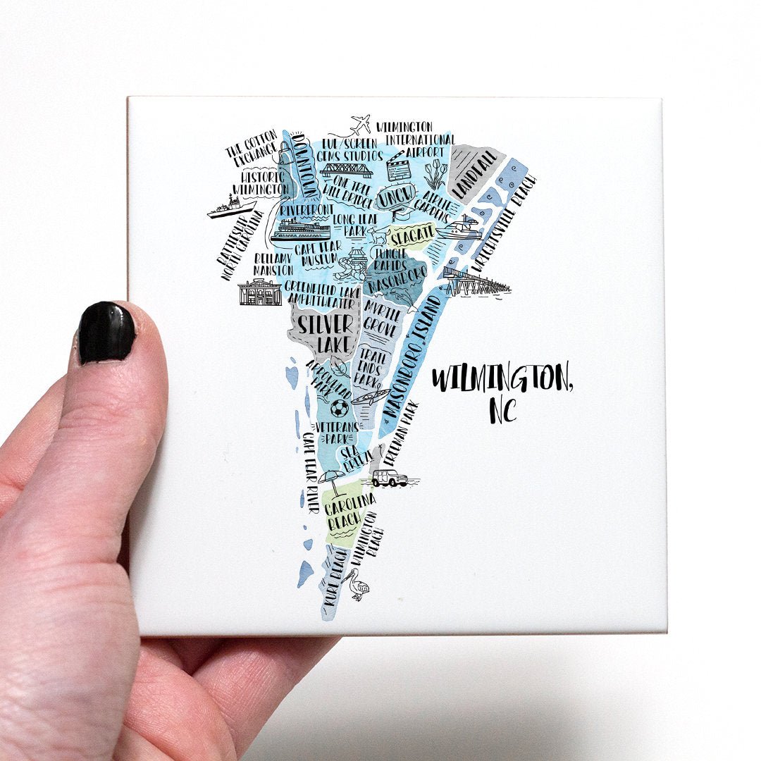 A hand holding a coaster with an illustrated map of Wilmington NC on it - in the color blue