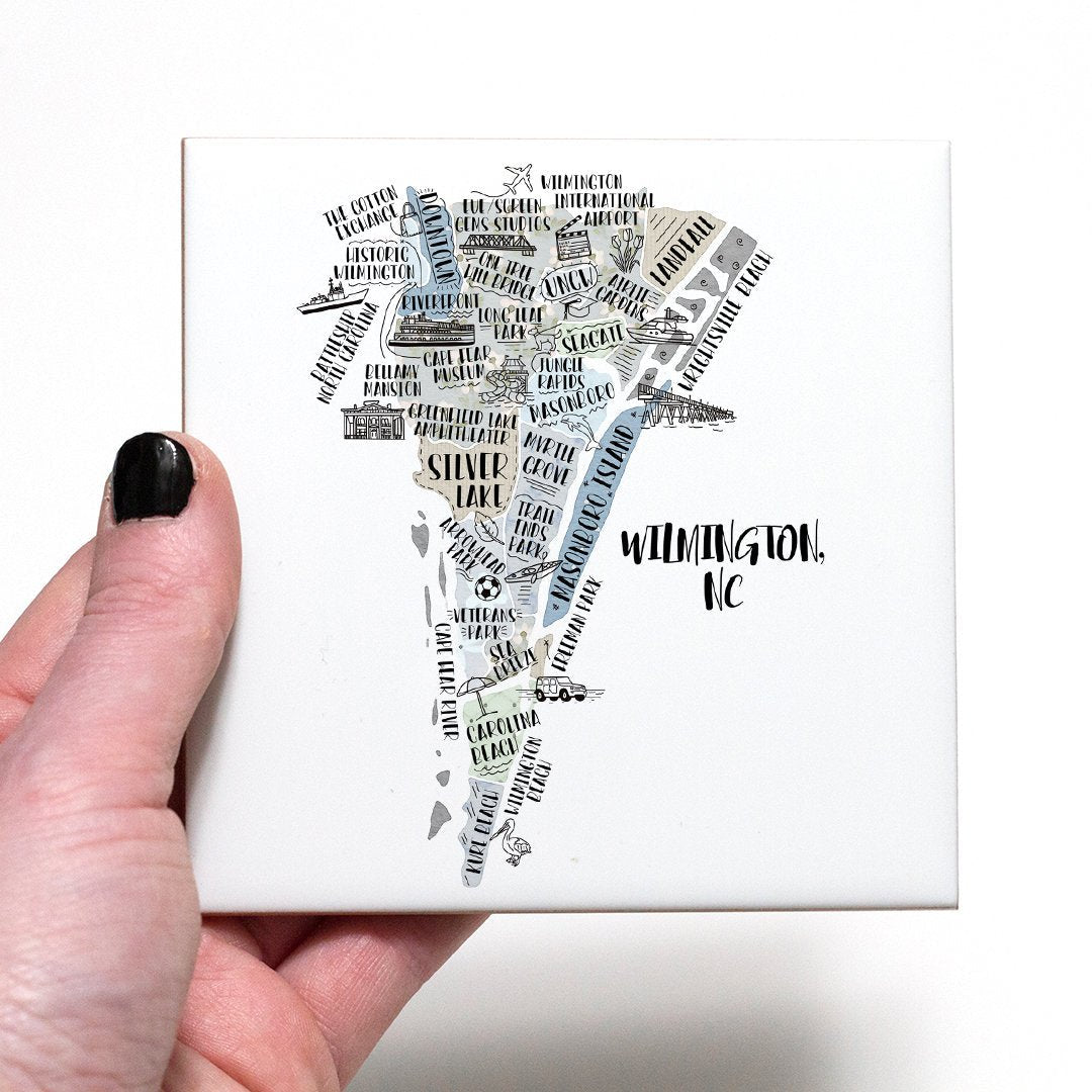 A hand holding a coaster with an illustrated map of Wilmington NC on it - in the color gray