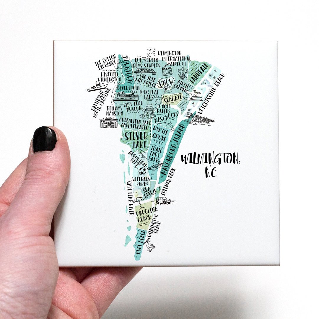 A hand holding a coaster with an illustrated map of Wilmington NC on it - in the color teal