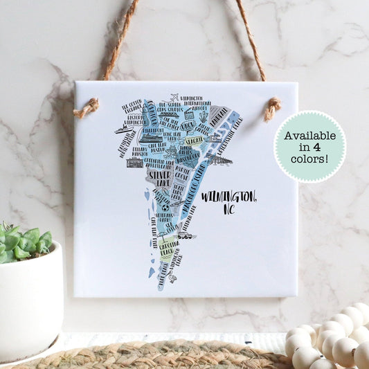 A hand-drawn tourist map of Wilmington North Carolina on a square tile sign hanging on a wall - Sparks House Co