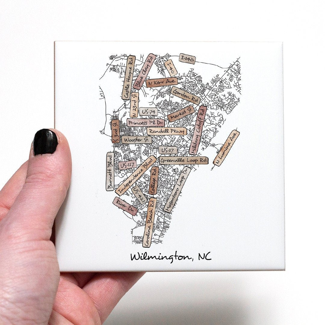 A hand holding a ceramic coaster with a street map of Wilmington NC on it - in the color boho